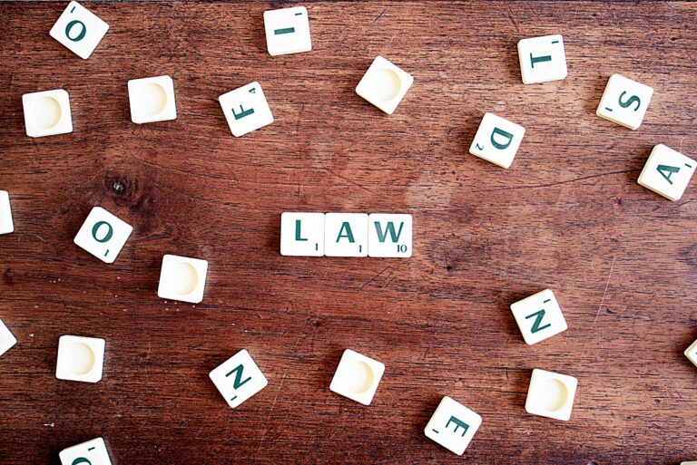 Scrabble tiles spelling 'LAW' on a wooden table, symbolizing connections to education and legality.